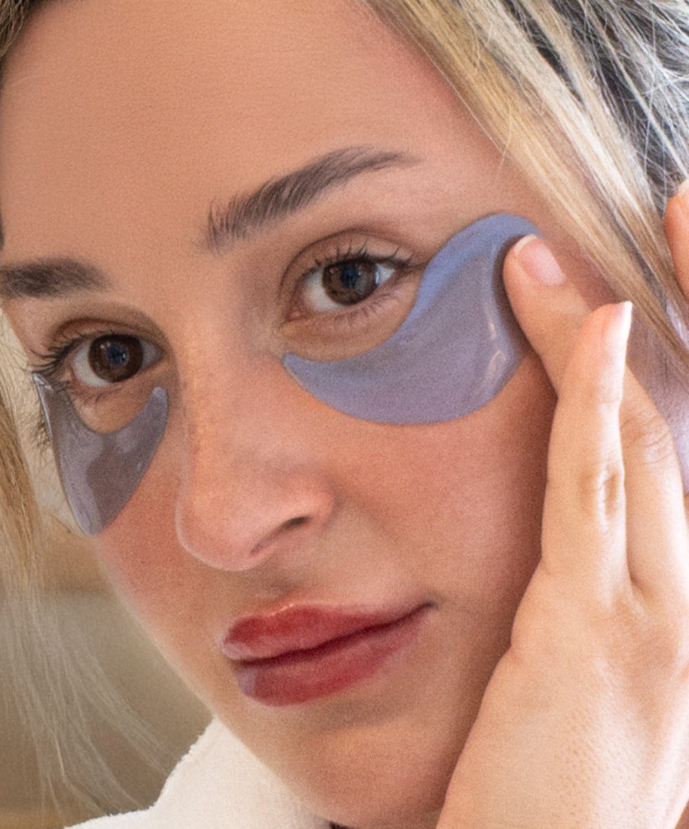 Woman applying eye patches to her face