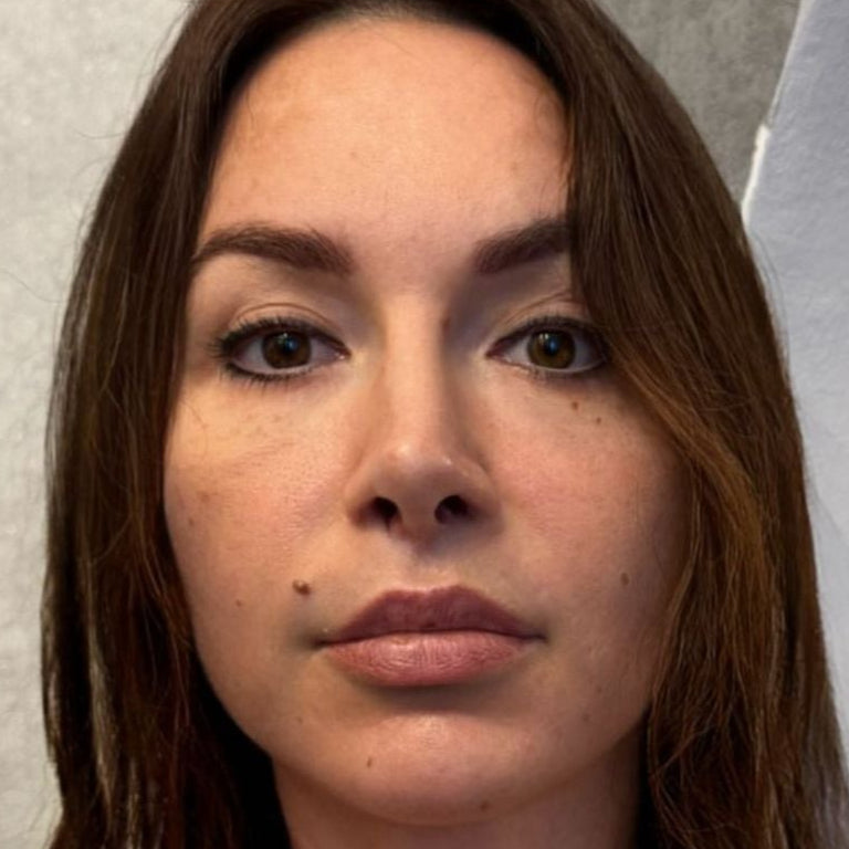 Woman with a tattoo on her neck standing against a neutral background